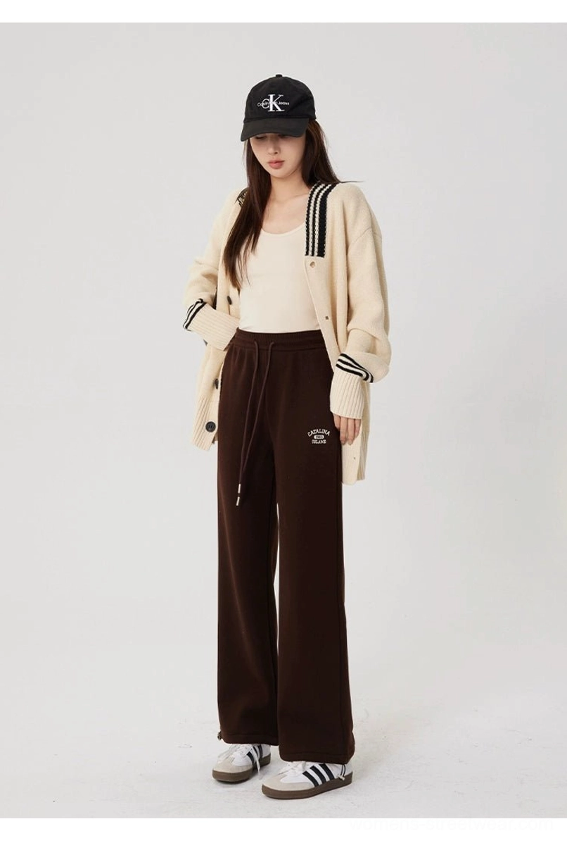 Full-body front styling of brown fleece-lined straight-leg sweatpants with a black baseball cap, knit cardigan, and casual striped sneakers