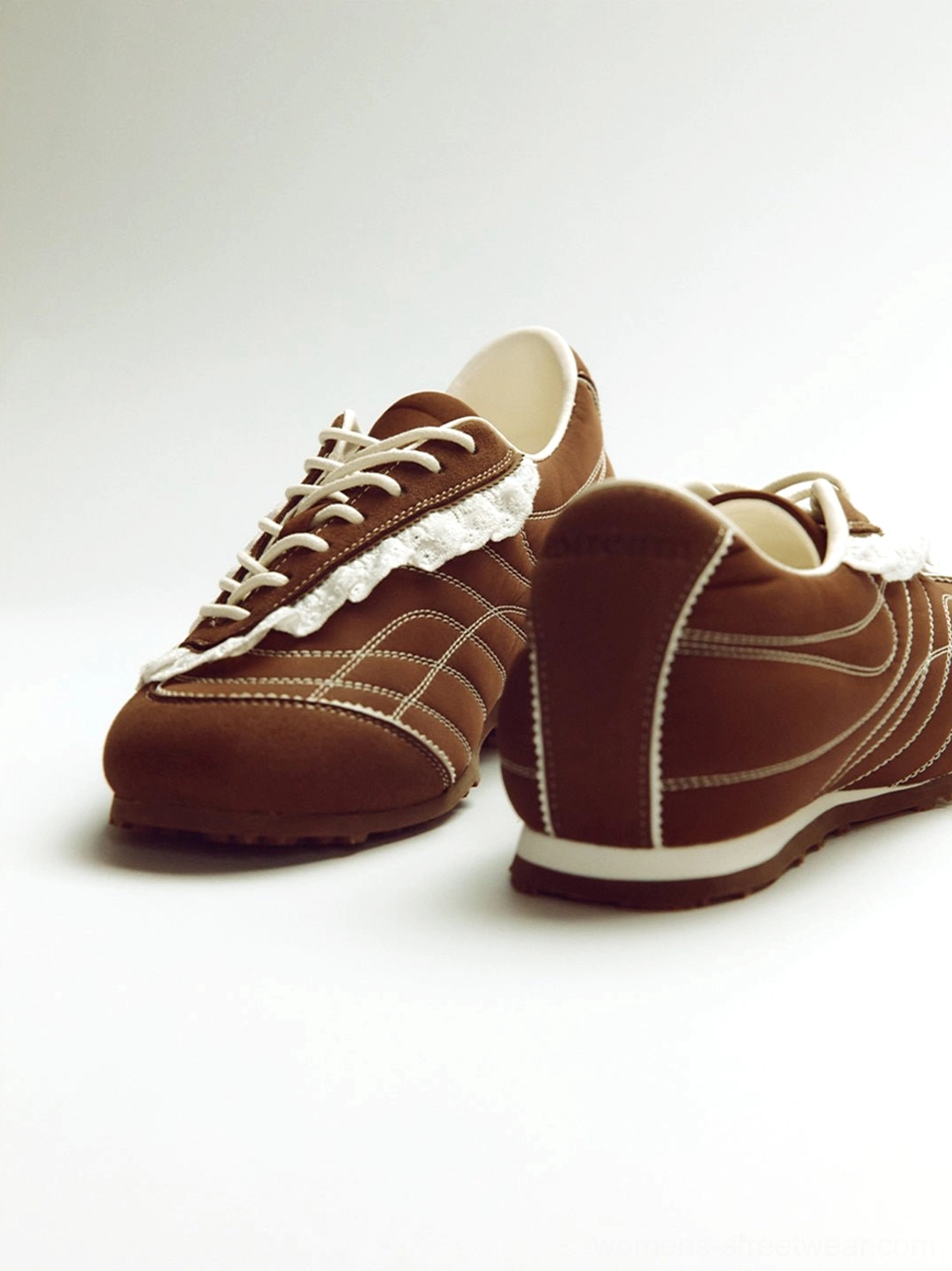 Brown frilled trainer sneakers displayed from front and rear angles with white midsoles contrast stitching and reinforced toe design