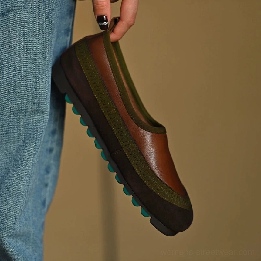 Side profile of brown green casual leather slip-on shoes displayed with blue denim, showing the smooth upper and rugged textured outsole