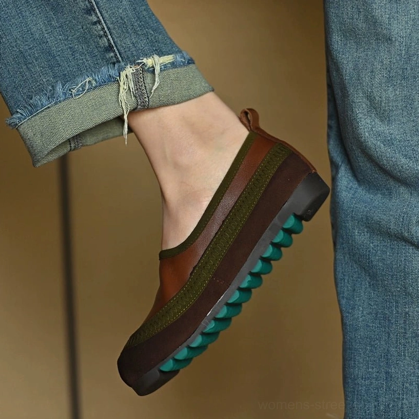 Brown green slip-on shoe worn with rolled blue jeans, highlighting the raised heel area and textured green traction outsole