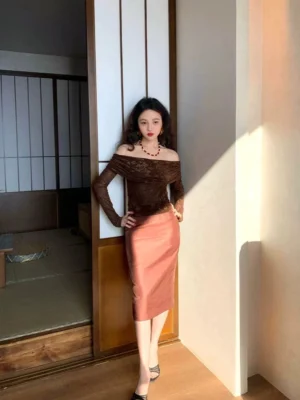 Brown high-waisted satin midi pencil skirt shown in a front full-body view with a sleek fitted silhouette in a warm Japanese-inspired wooden corridor