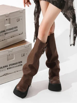 Female model wearing brown knee-high platform boots with relaxed stacked cuffs and chunky black soles