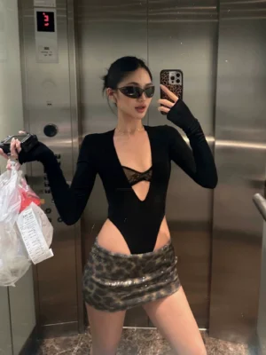 Three quarter view of brown leopard print sequin mini skirt with black cutout bodysuit and sunglasses