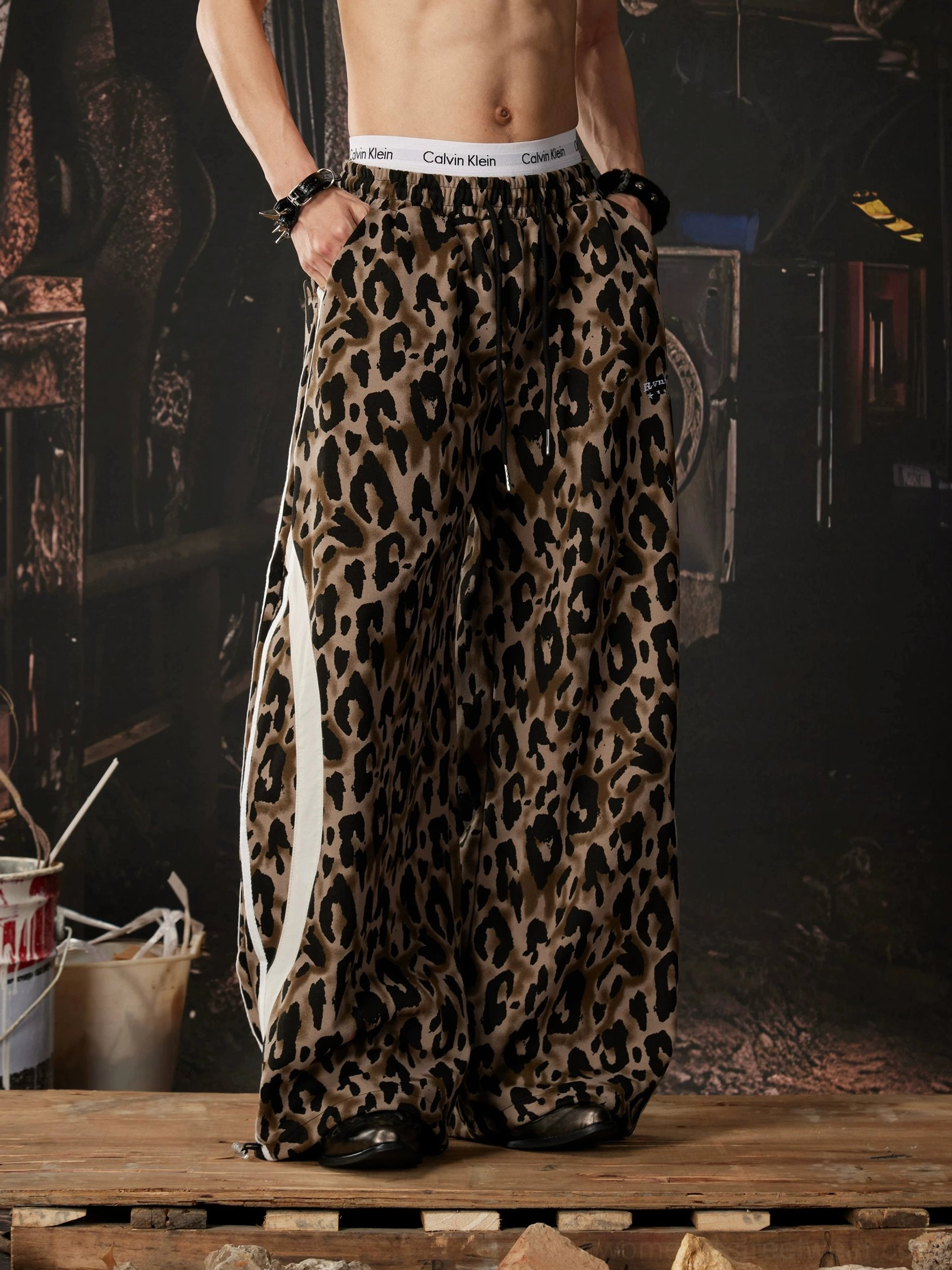 Side profile of brown and black leopard print wide leg track pants with contrasting white athletic stripe