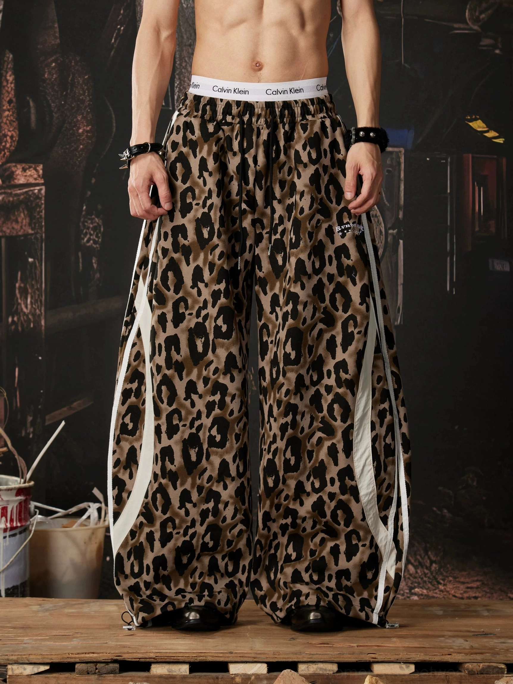 Front view of brown leopard print track pants with wide legs white racing stripes and elastic drawstring waist