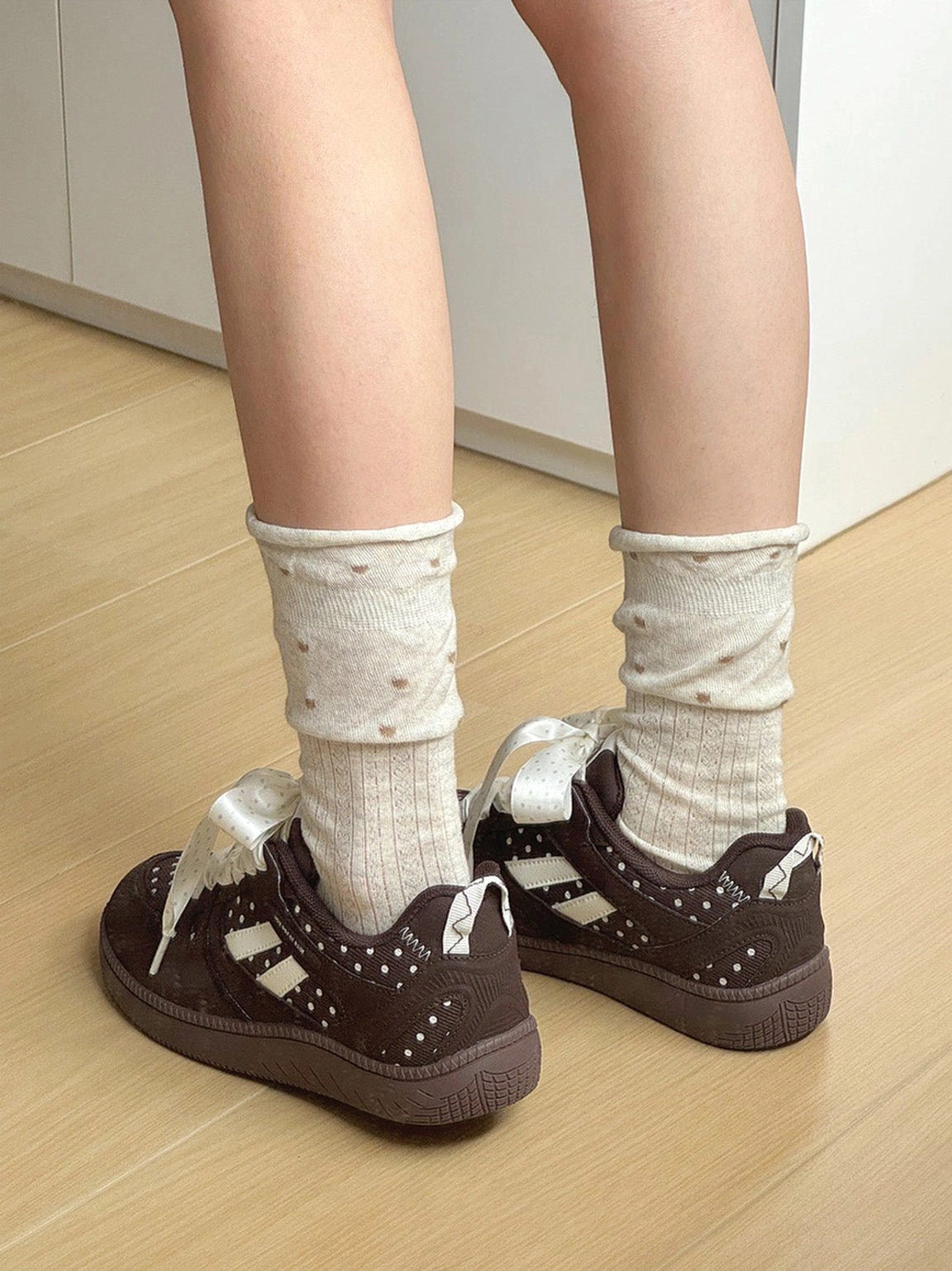 Brown low top polka dot skate shoes worn as a coordinated pair with dotted socks and rubber outsoles
