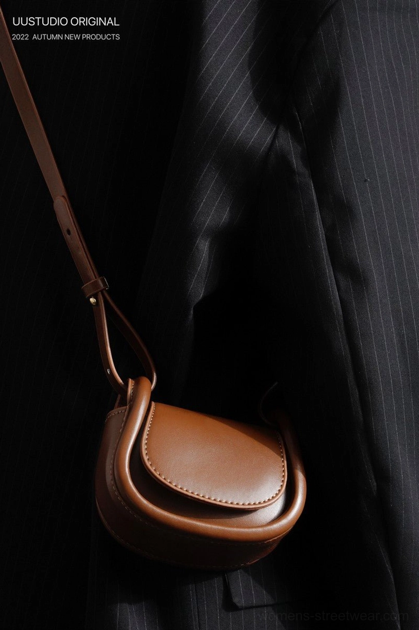 Brown mini saddle crossbody bag with adjustable strap styled with black tailored streetwear