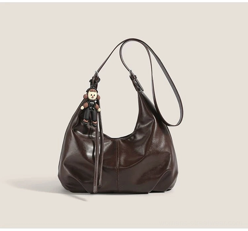 Brown monkey charm hobo bag shown from the side with adjustable shoulder strap and relaxed folded faux-leather construction