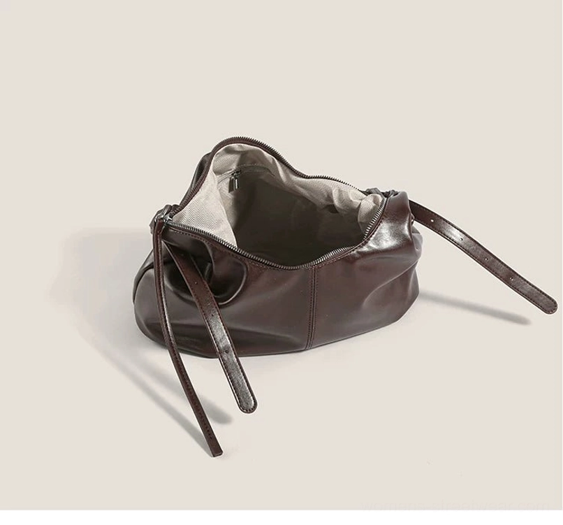 Open interior view of a brown monkey charm hobo bag showing the light fabric lining, zip-top compartment, and interior zip pocket