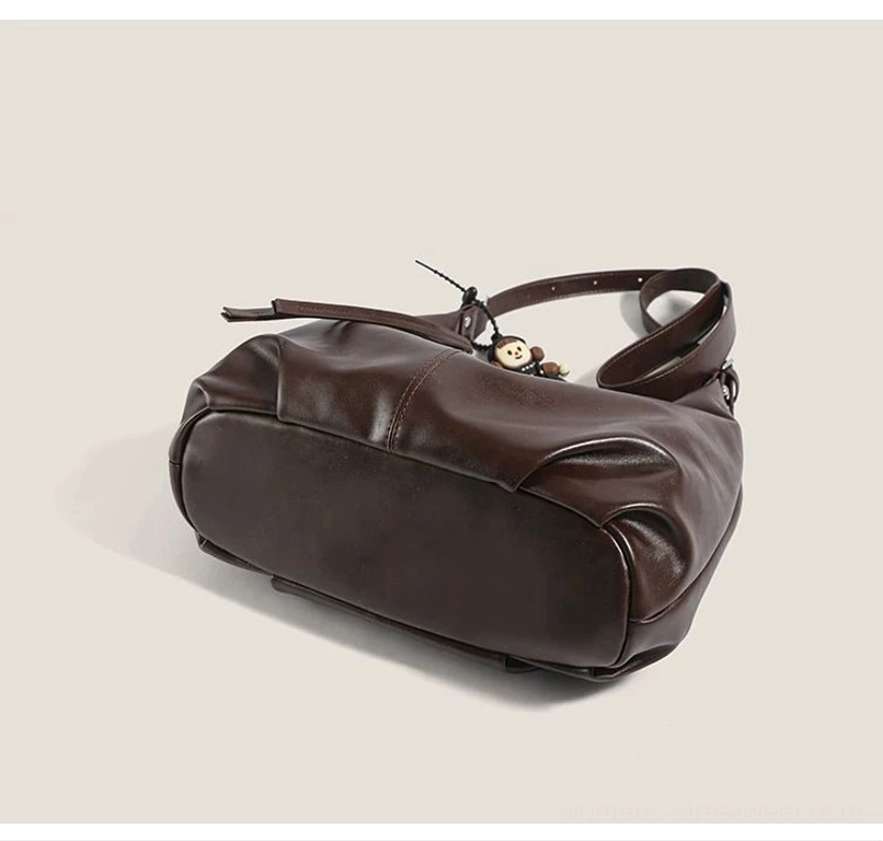 Bottom rear view of a brown monkey charm hobo shoulder bag showing the flat base and clean faux-leather construction