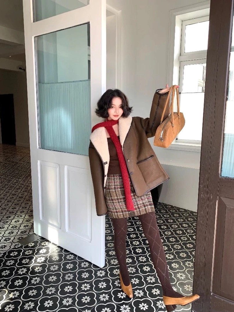 Three-quarter view of a brown oversized sherpa button jacket styled with a red scarf, plaid mini skirt, textured tights, and vintage East Asian streetwear details
