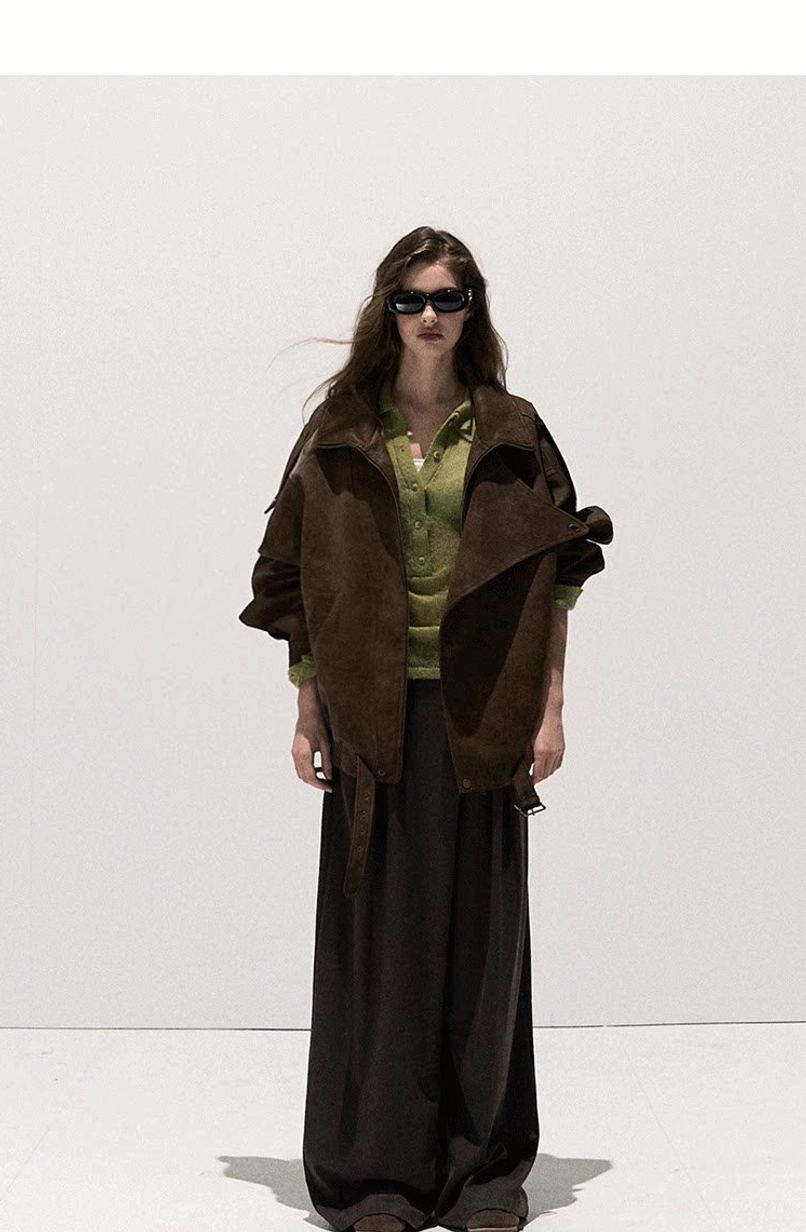 Front full-body view of a brown oversized suede-look moto jacket with classic lapel collar, natural drape, adjustable hem, green knit top, and wide-leg trousers
