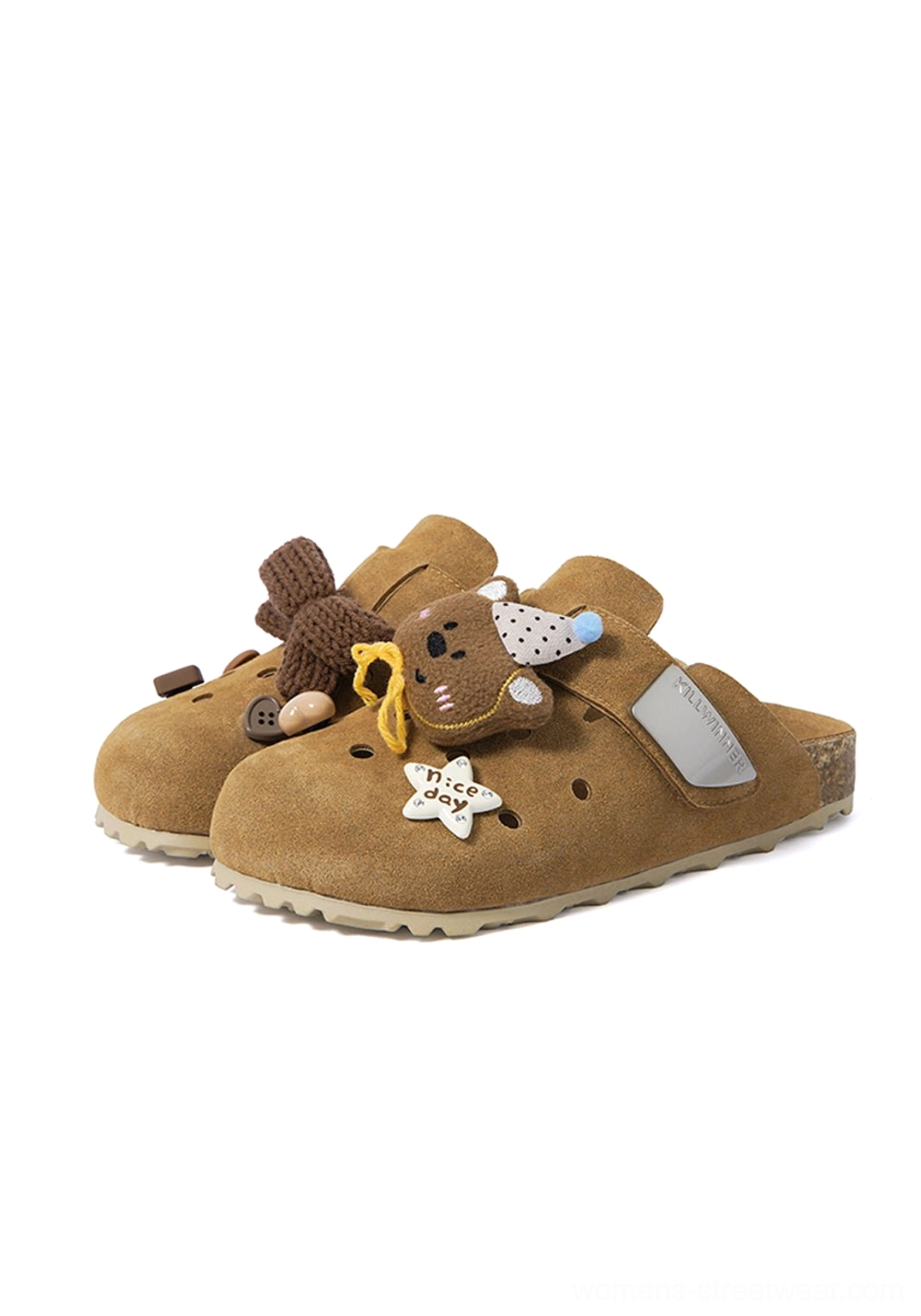 Front flat lay of brown perforated clogs with knit bow, bear charm, star decoration, open heel, and molded cork-look footbed