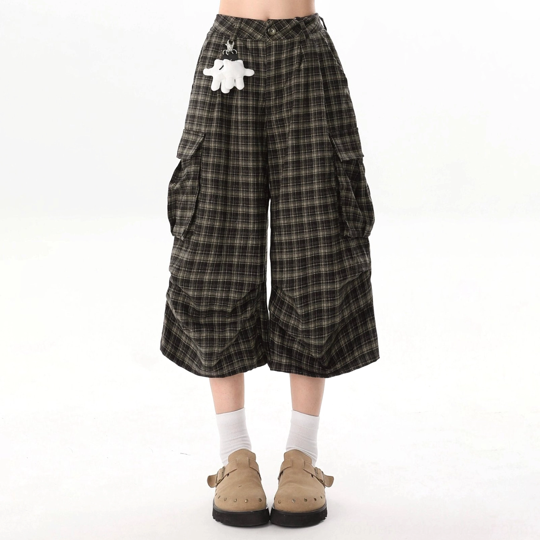 Detailed front view of brown plaid wide-leg cargo culotte shorts with button waist closure, oversized cargo pockets, cropped legs, and white character pendant