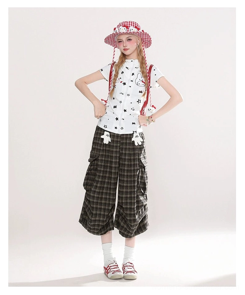 Young woman styling brown plaid wide-leg cargo culotte shorts with a playful plush charm, star graphic shirt, white socks, and red sneakers