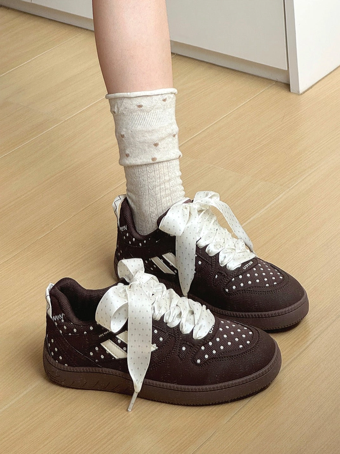 Pair of brown polka dot ribbon skate sneakers displayed with matching dotted socks and thick rubber soles