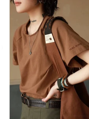 Brown raglan sleeve crew neck t-shirt with double-layered collar and raw edge details, styled with bohemian accessories and canvas shoulder bag