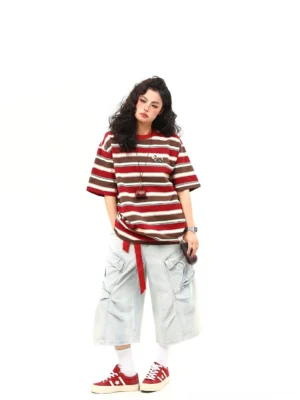 Front full-body view of a brown red striped oversized T-shirt styled with cropped wide-leg jeans and red casual sneakers