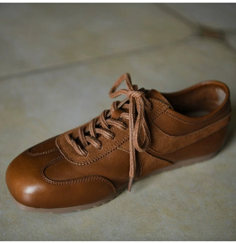 Brown leather retro sneakers shown from the front three-quarter angle with suede toe cap, suede lace panel, rounded toe, and neat stitching