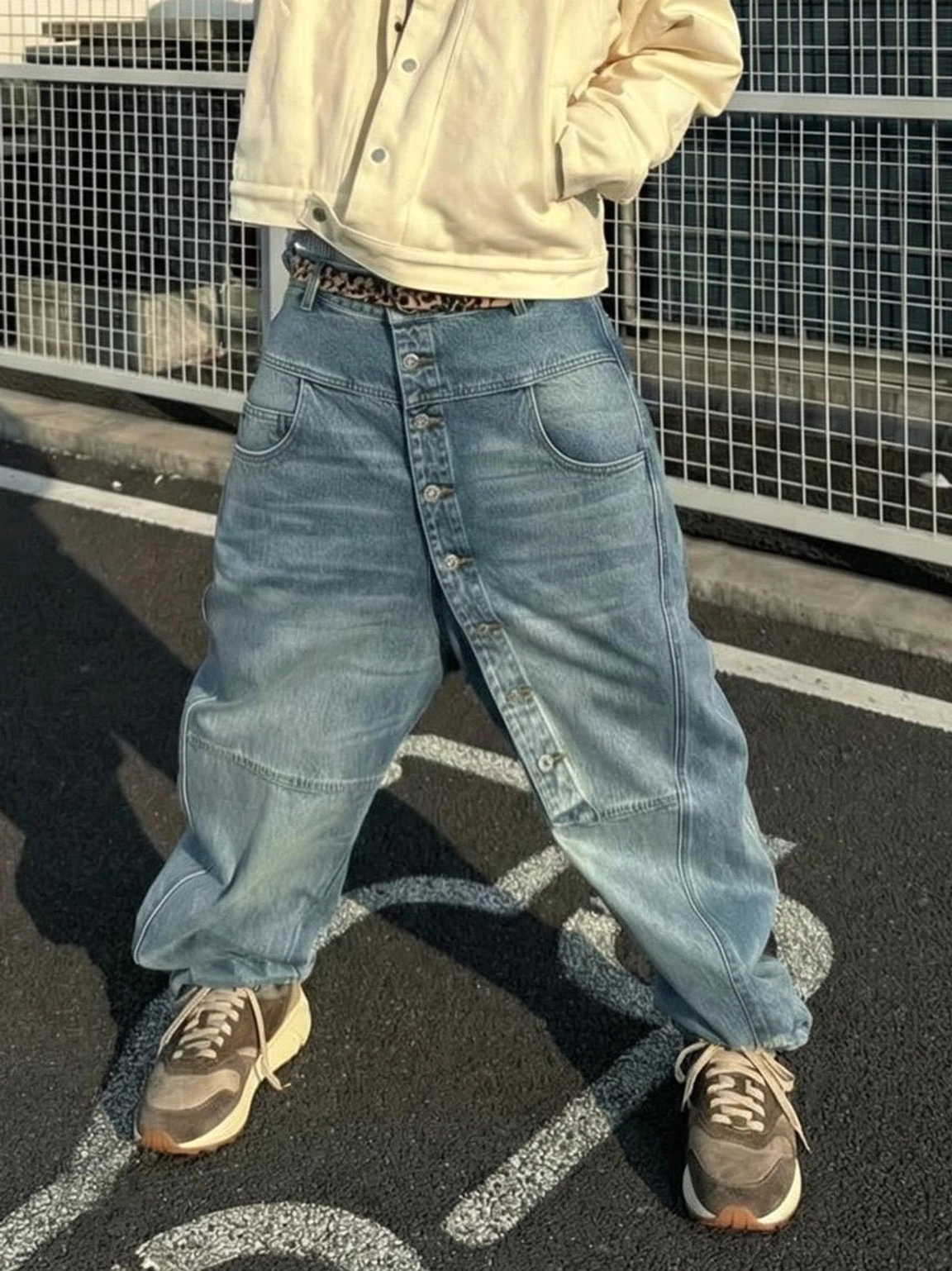 Front view of model wearing brown retro trail runner sneakers with cropped top and high waisted baggy jeans