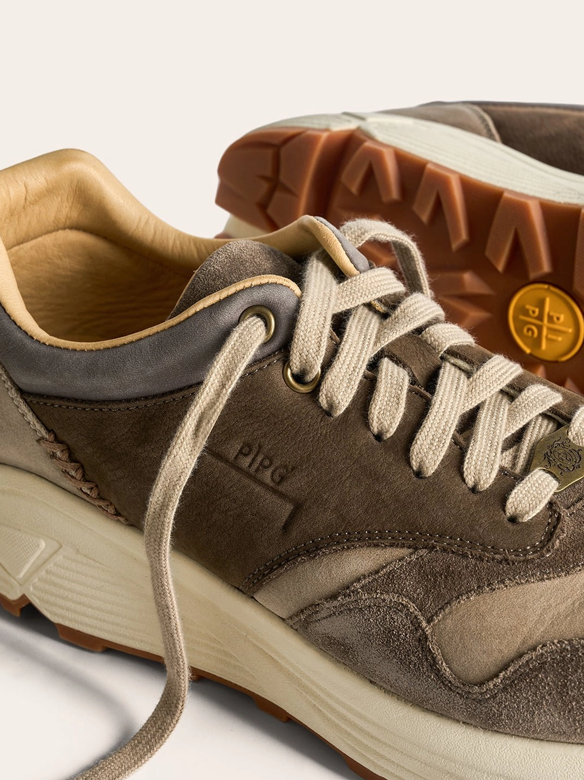 Side close up of brown retro trail sneaker with stitched heel trim leather lining and lugged rubber outsole