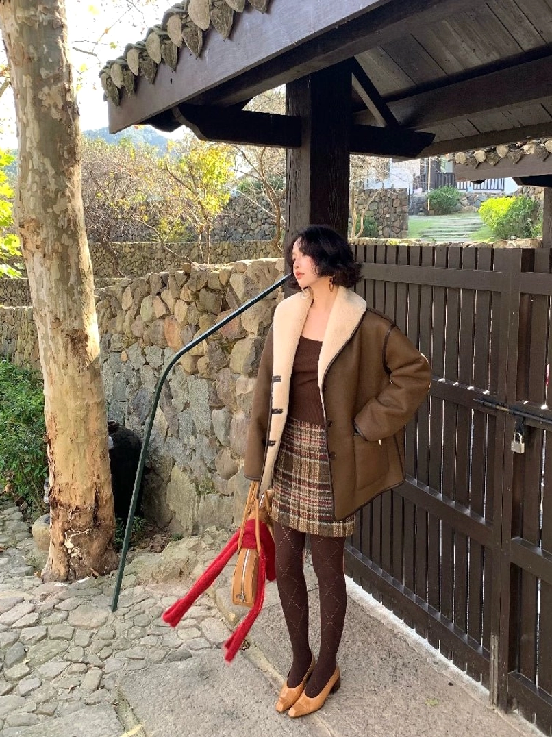 Side view of a brown oversized reversible fleece jacket showing the faux leather-inspired exterior, cream shearling lining, contrast collar, and relaxed Korean streetwear silhouette