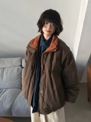 Front three-quarter view of brown reversible padded jacket with stand collar snap closure elastic hem and relaxed Korean streetwear fit