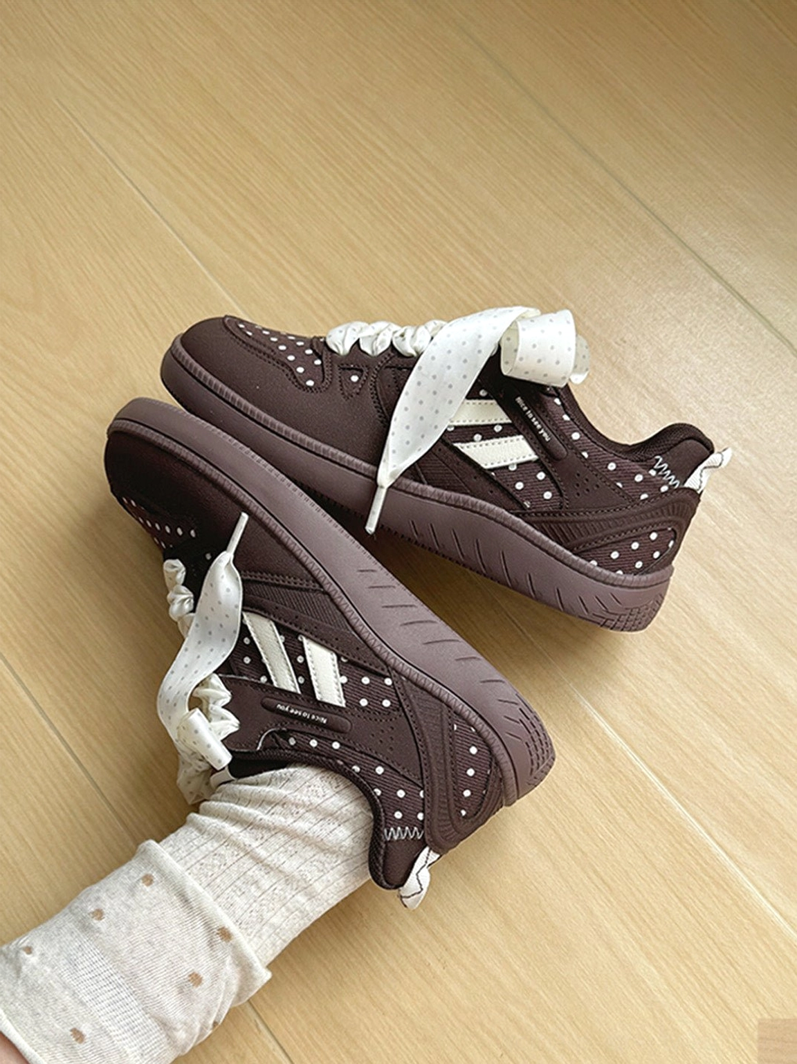 Overhead view of brown ribbon lace skate sneakers worn with polka dot socks and casual streetwear