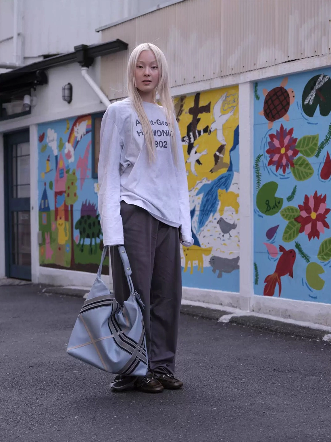 Brown ruched square toe buckle flats styled with casual outfit in front of colorful street art wall