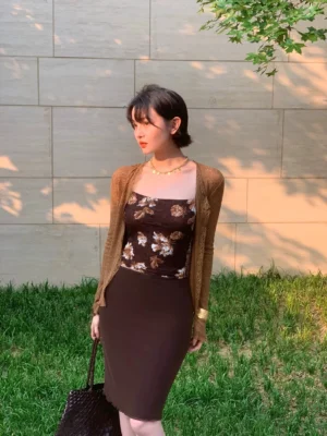 Brown sheer button-up cardigan with cropped slim fit and flared sleeves styled with a floral camisole and brown midi skirt outdoors