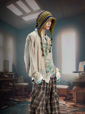 Male model wearing a brown sheer layered shirt sweater with green vintage graphics, loose fit styling, and plaid cargo pants in a Korean streetwear inspired outfit