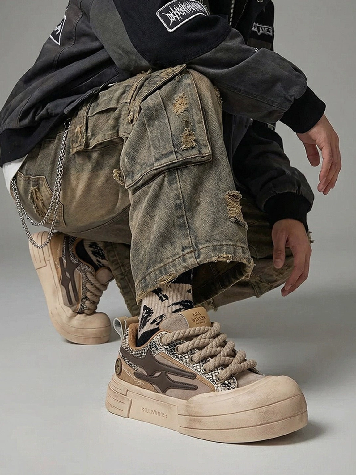 Brown chunky platform sneakers worn with distressed green cargo pants and patterned socks in oversized streetwear look