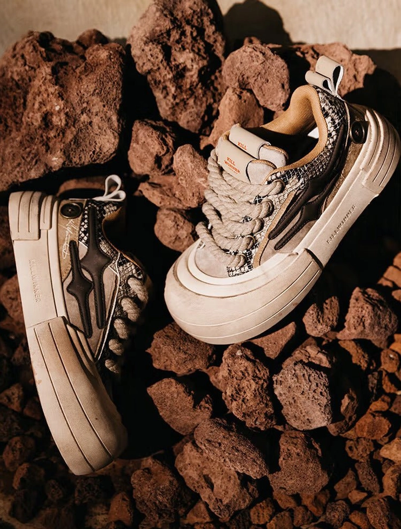 Brown platform sneakers flat lay on volcanic rocks showing heel pull tab lightning side detail and chunky outsole
