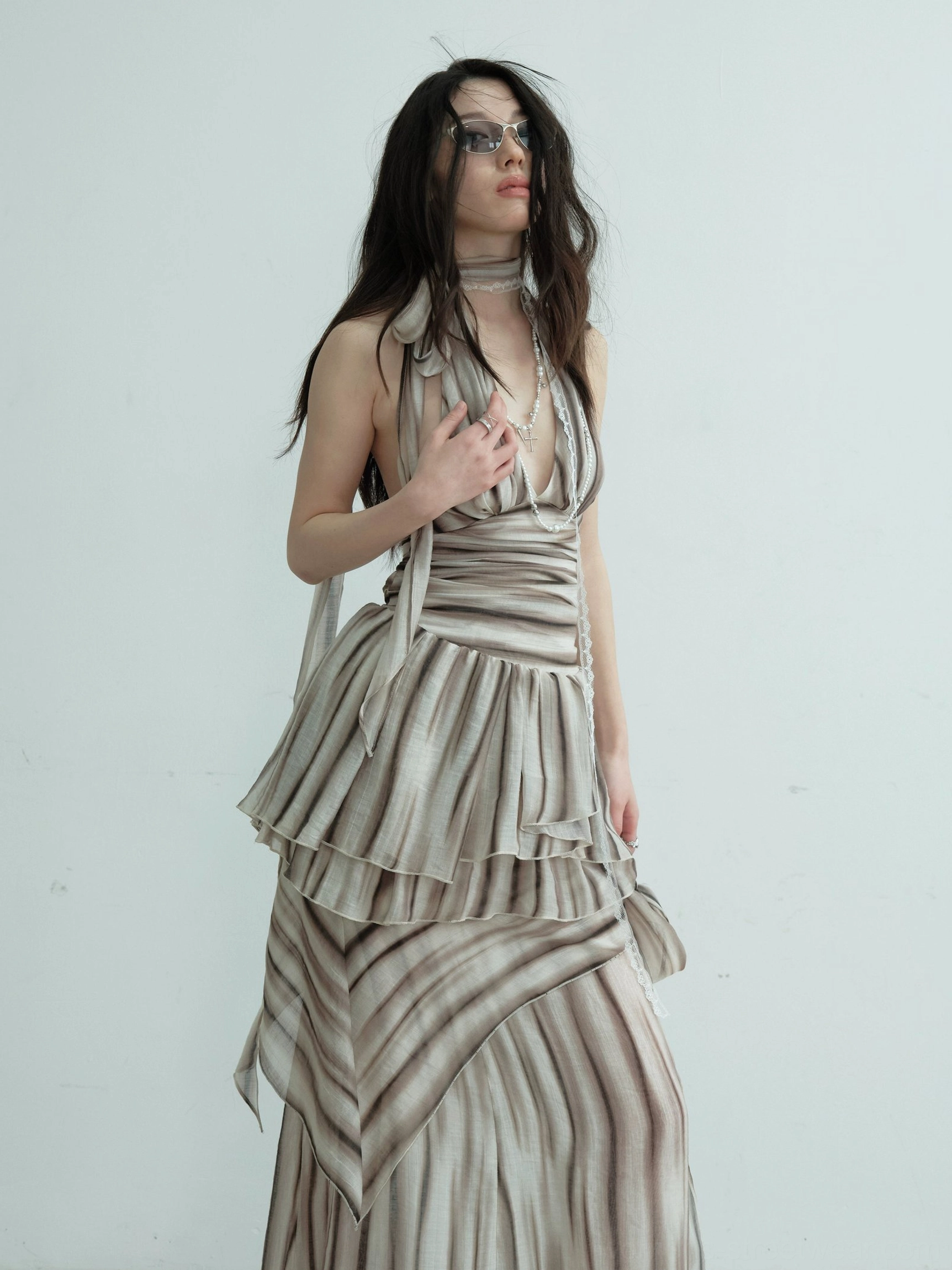 Close-up view of brown striped halter dress set showing the deep V neckline, layered ruffled waist, matching maxi skirt, sunglasses, and choker