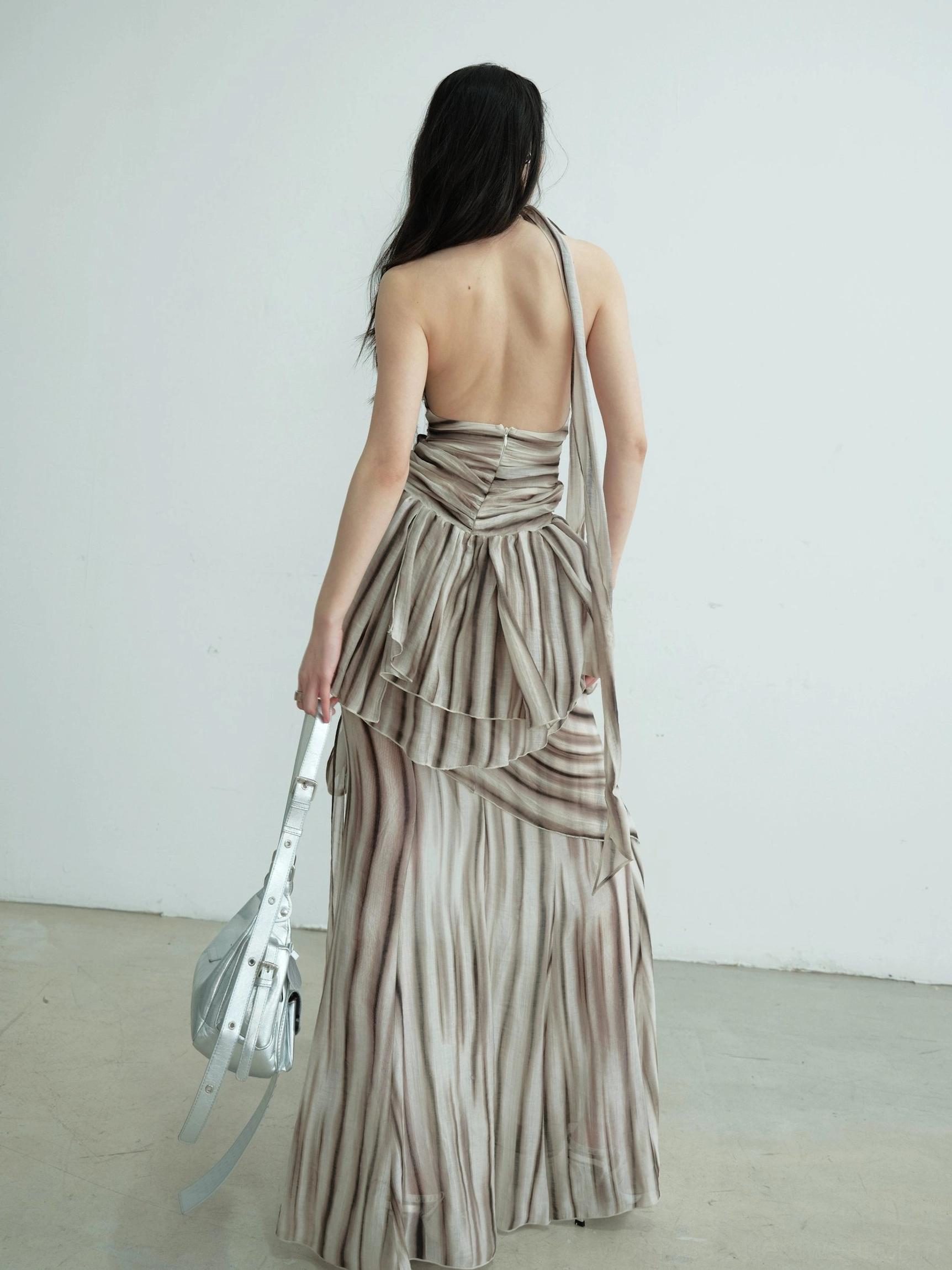 Back view of brown striped halter two-piece dress set featuring an open back, ruched waist, and draped floor-length skirt