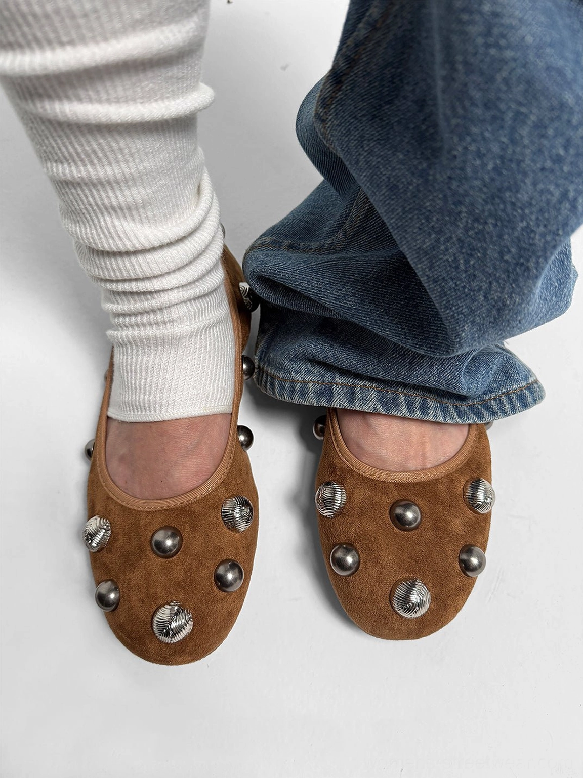 Brown studded ballet flats styled with blue wide-leg jeans and white ribbed socks in a casual streetwear outfit