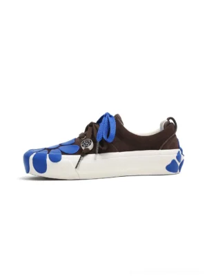 Side profile of brown suede asymmetric platform sneakers with bright blue double laces, blue daisy toe details, flower outsole accents, and metallic lace charm