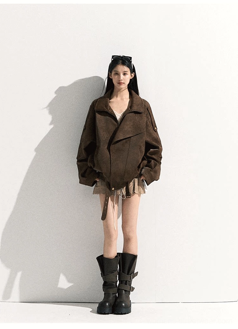 Full-body fashion view of a brown suede-look oversized moto jacket with drawstring hem, mini skirt, combat boots, and retro sunglasses