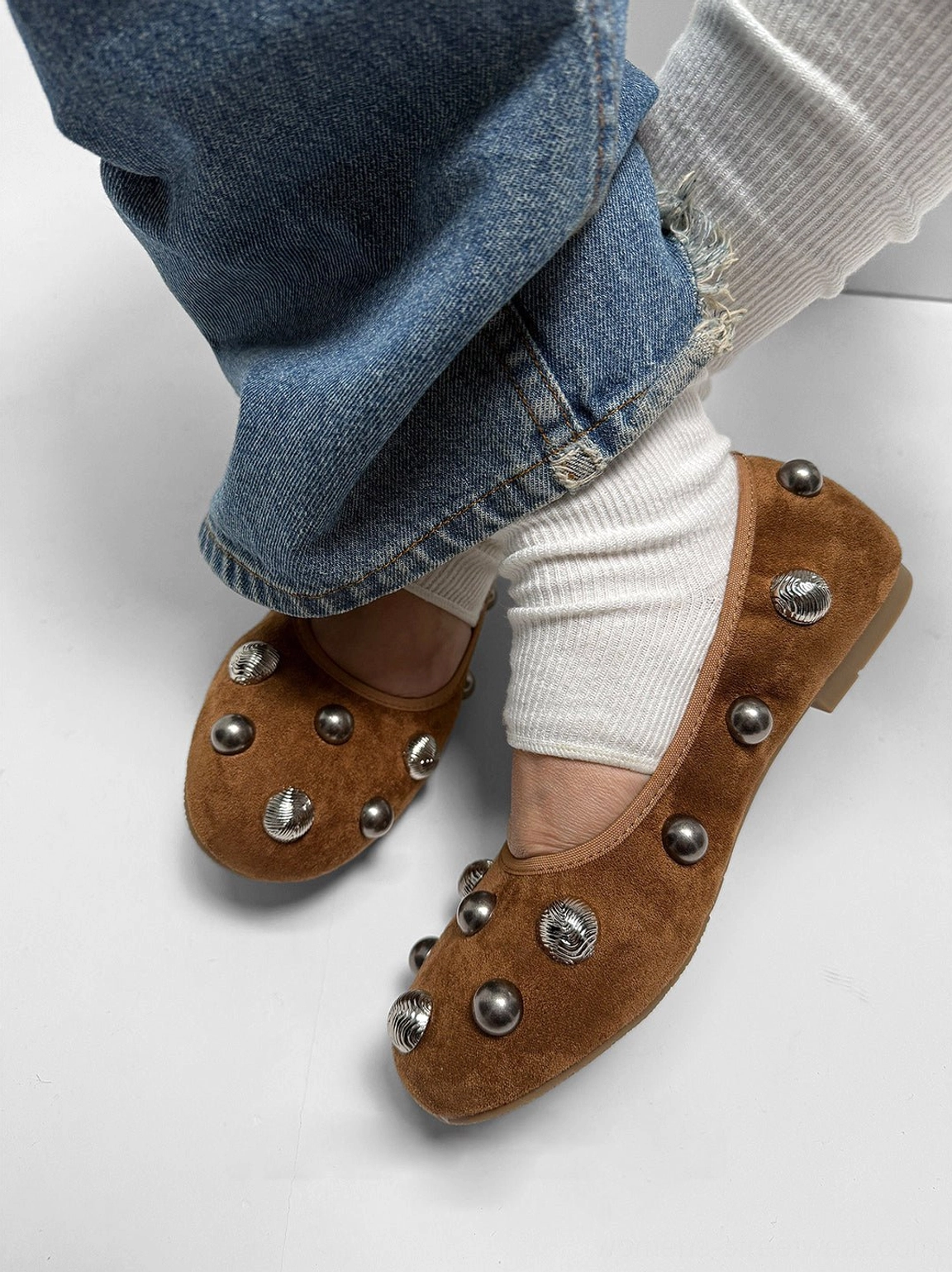 Three-quarter view of brown suede-look studded ballet flats worn with blue denim jeans for a Korean-inspired casual outfit
