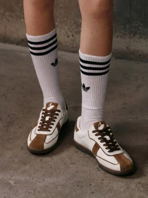 Brown suede and white leather gum sole retro trainers worn with striped crew socks in low angle streetwear close-up
