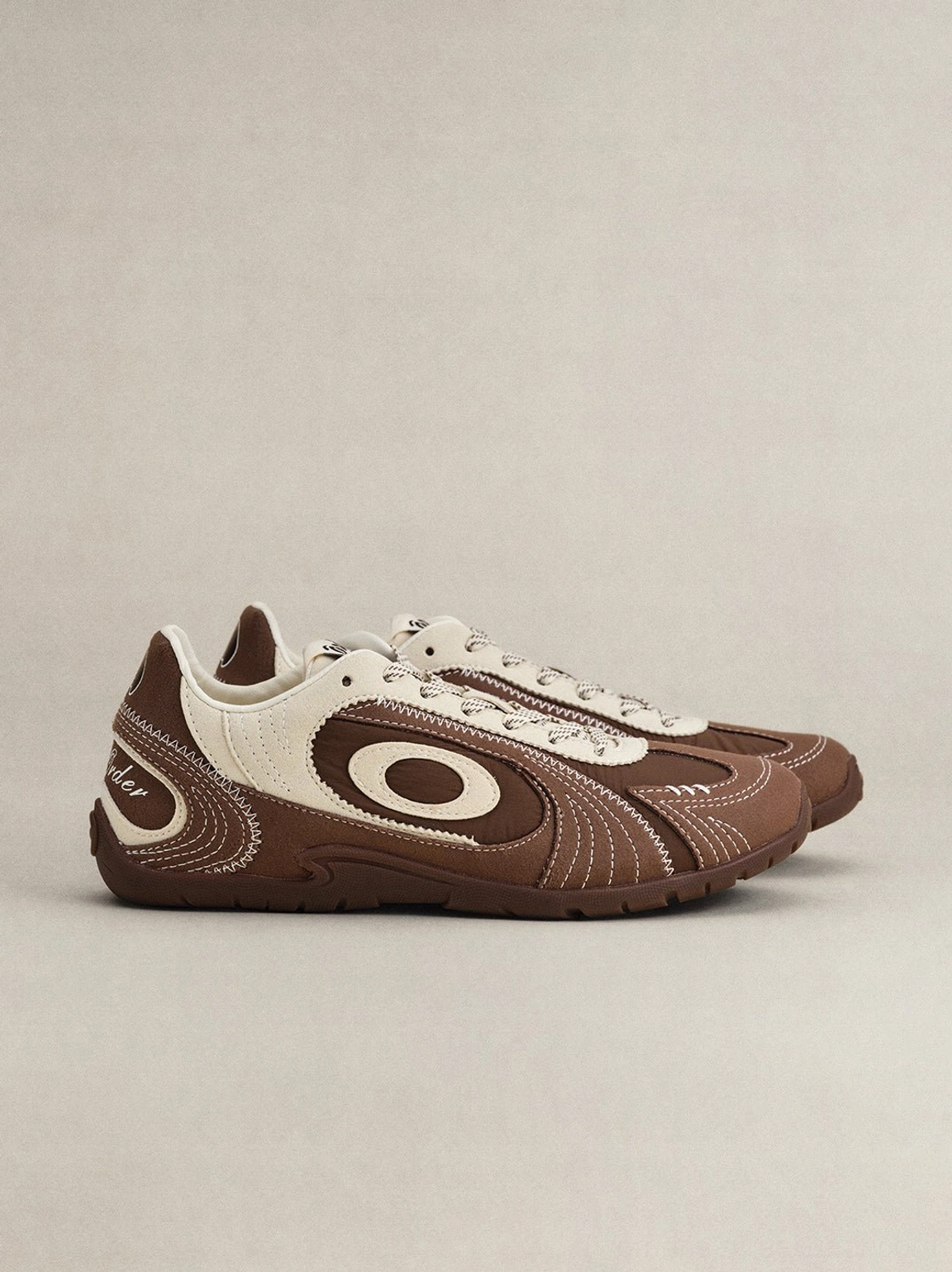 Brown swirl panel retro trainers with cream overlays and dog-shaped side charm product detail view