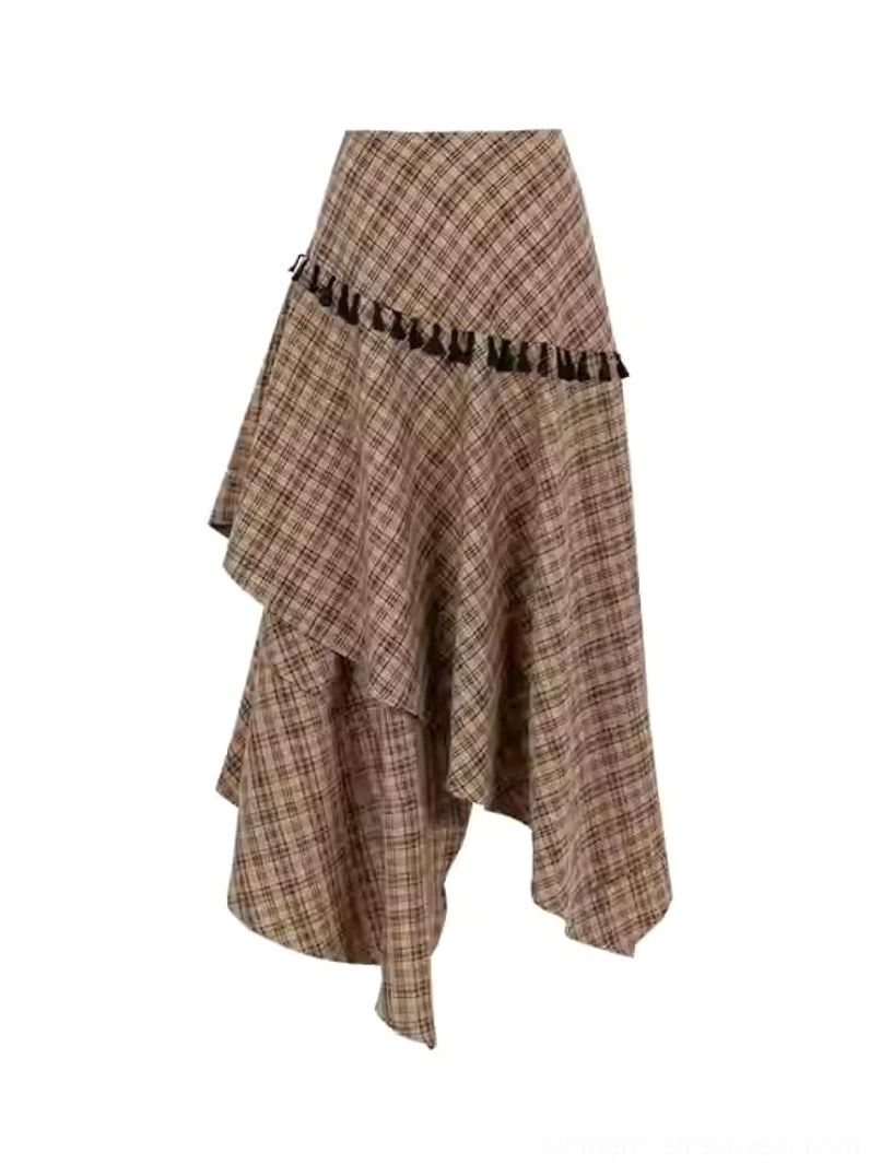 Flat lay front view of brown tartan asymmetric tassel skirt showing the irregular hem and black decorative trim on a plain background
