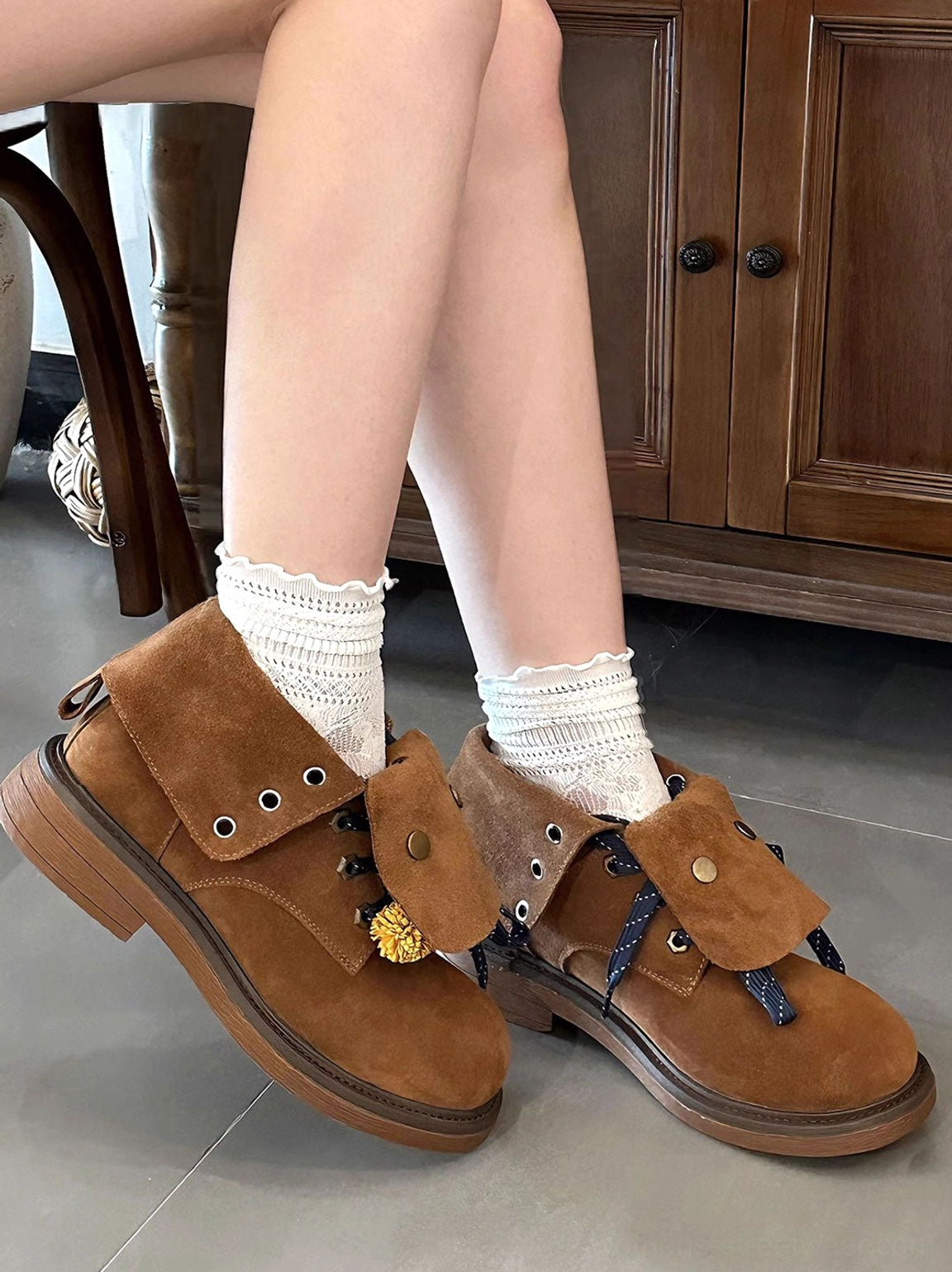 Brown suede-look tassel ankle boots worn with white ruffled socks in a vintage indoor setting, showing relaxed Korean streetwear styling