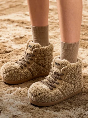 Model wearing brown teddy fleece high-top platform boots with taupe socks on a soft shag rug, front view