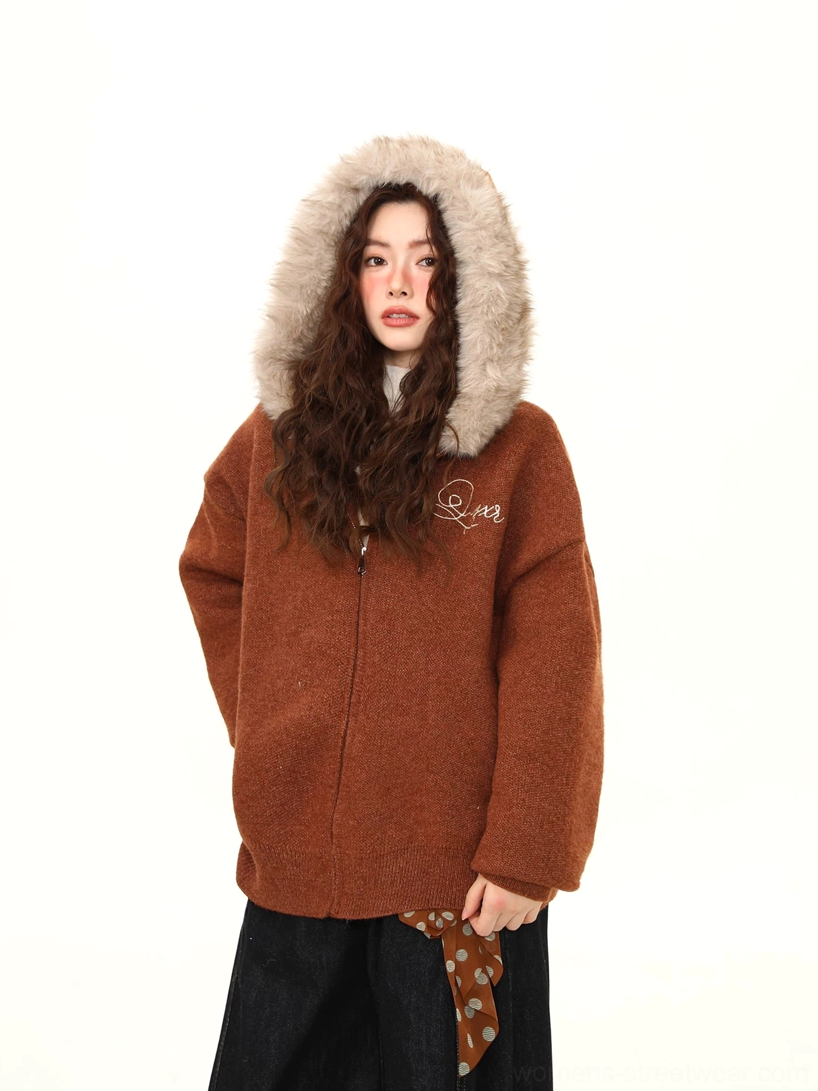Close front view of a brown streetwear teddy jacket showing the plush faux-fur hood trim, metal zipper, and chest embroidery