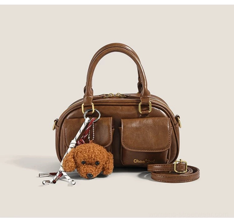 Brown vintage pocket satchel with plush puppy charm dual front flap pockets and detachable crossbody strap flat front view