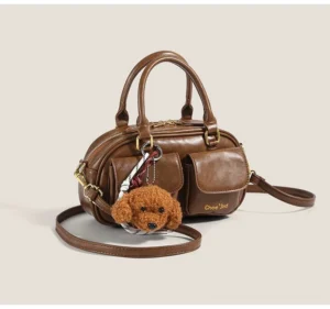 Brown vintage puppy charm pocket bowling crossbody bag with gold-tone hardware and detachable shoulder strap front three-quarter view