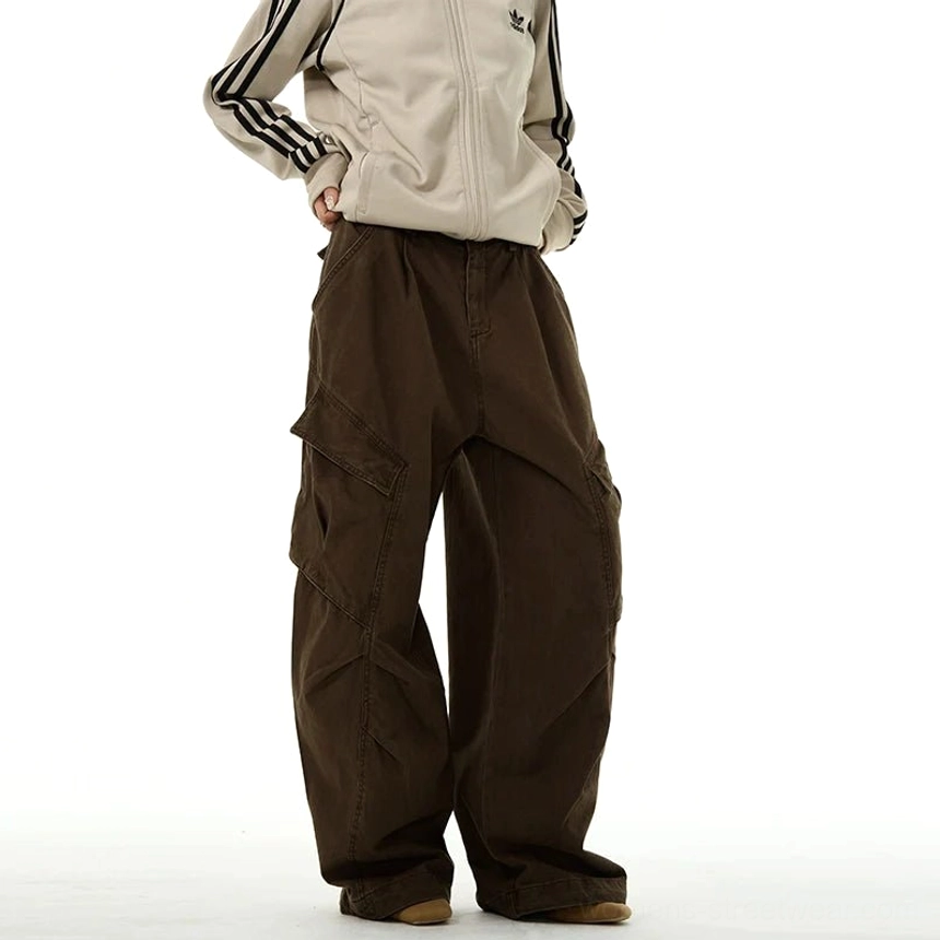 Brown wide-leg streetwear cargo pants shown from the side on a male model, highlighting the washed finish, pleated legs, relaxed fit, and oversized cargo pockets