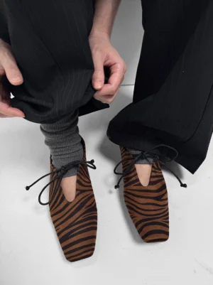 Brown zebra-print square-toe loafers styled with grey ribbed socks and black pinstripe wide-leg trousers in a Korean streetwear outfit