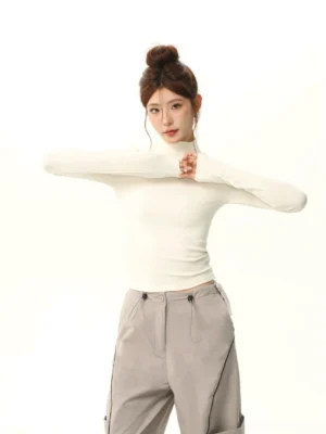 Off-white brushed mock neck slim fit long sleeve streetwear top styled with grey wide-leg cargo pants on a female model